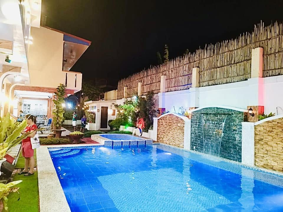 Pool lit at night with waterfall wall and bamboo fence